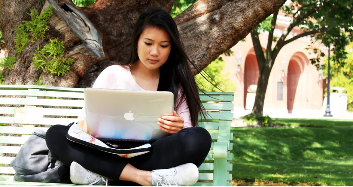 Student on bench with laptop